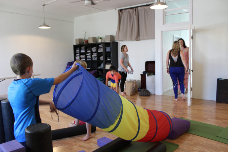 Children build a fort inside Body Bliss yoga studio on July 26, while studio owner Jacquie Michelle (center) talks to employee Phoebe Schram (right).