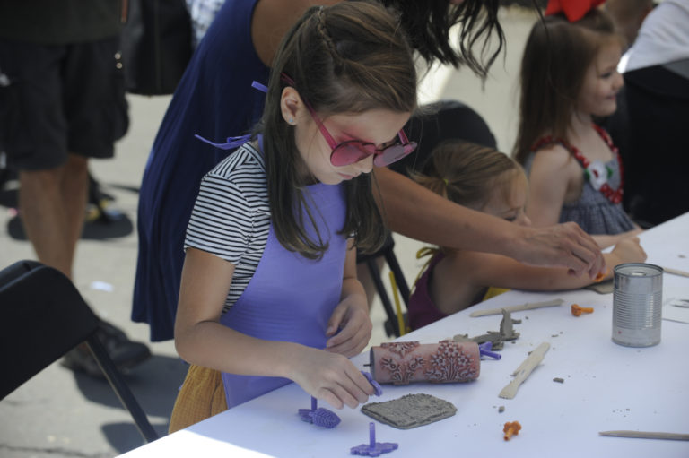 At right, a young artist learns some tricks about clay art from local artists at the Picnic in Color event, held Sunday, July 28, in downtown Camas.