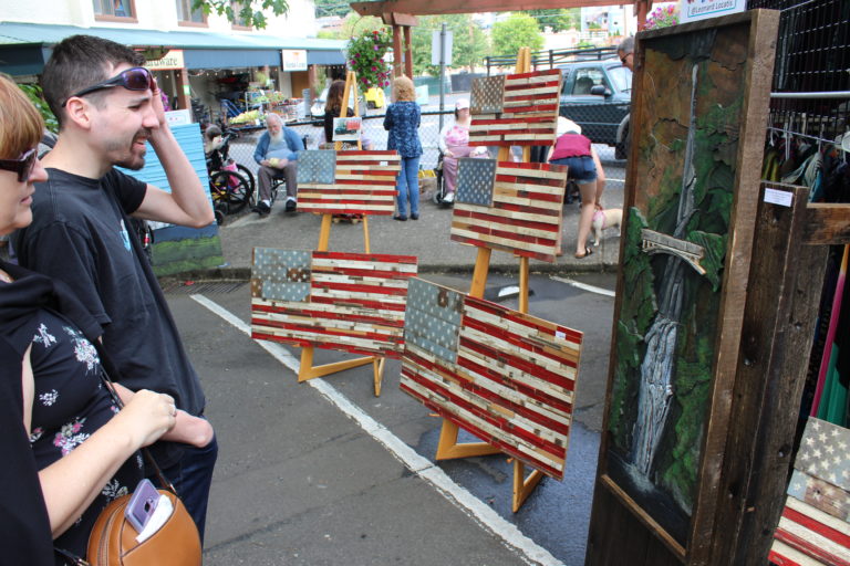 A Camas Days attendee examines a reproduction of the Multnomah Falls area for sale Saturday. July 27.