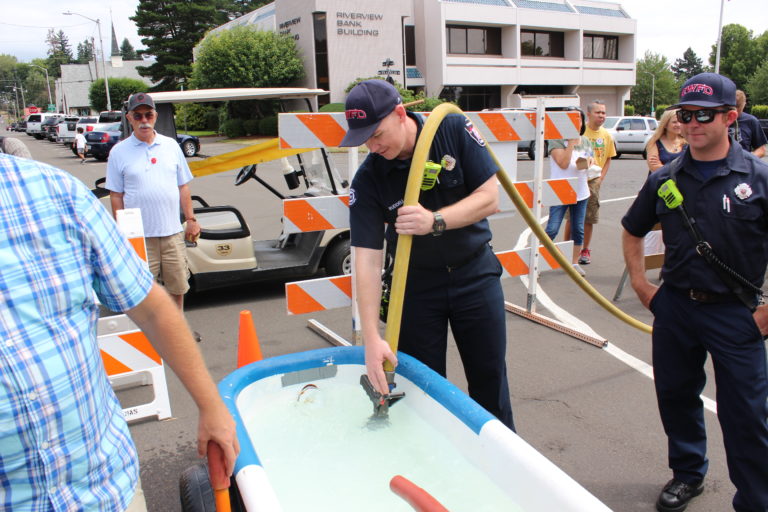 Chris Ruddell of the Camas-Washougal Fire Department fills a bathtub with water before the first race of the Bathtub Races on Saturday, July 27.
