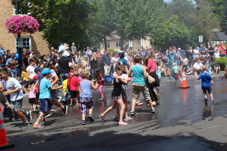 Children are "accidentally" sprayed with water from a fireman's hose between bathub races on Saturday. July 27.