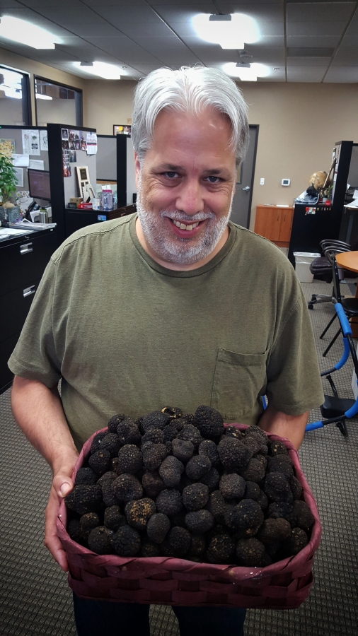 Francios de Melogue, a former chef who currently provides marketing services for Foods in Season, holds a basket of truffles.