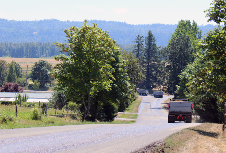 Trucks hauling material from a Washougal mine in the Columbia River Gorge National Scenic Area turn from Southeast 356th Avenue onto Evergreen Highway in July 2018, a few days after a truck coming from the rock quarry lost control and crashed onto railroad tracks across Evergreen Highway.