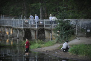 Hikers stroll across the Round Lake Dam while anglers go after trout. The pathway was closed on Aug. 20-21 while city crews replaced an old gear on the aging dam. (Wayne Havrelly/Post-Record)