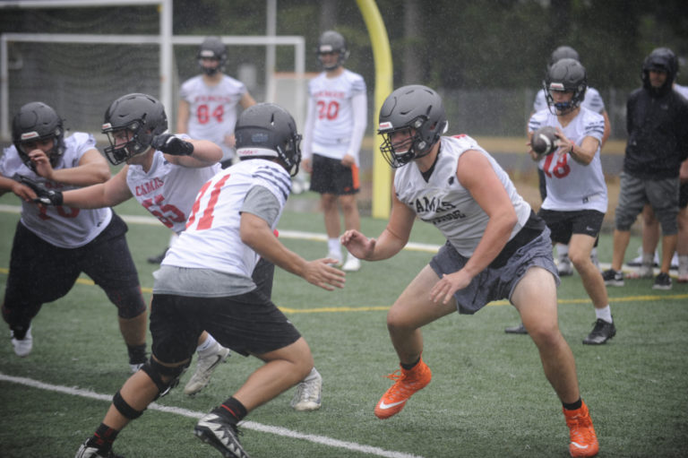 The Camas High School football team&#039;s first team on offense works on plays during a downpour at Cardon Field on the first day of practice, Aug.