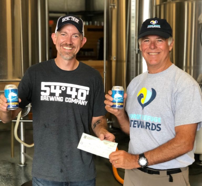 Bolt Minister (left), owner of 54-50 Brewing Company in Washougal, presents a check to Dave Pinkernell of the Columbia Refuge Stewards on Friday, Aug. 30, at 54-40 Brewing Company. Minister and Pinkernell are holding cans of 54-40&#039;s Restoration Ale, which was released earlier this year to raise funds and recognition for the U.S. Department of Fish and Wildlife&#039;s Steigerwald Lake National Wildlife Refuge habitat restoration and flood control project.