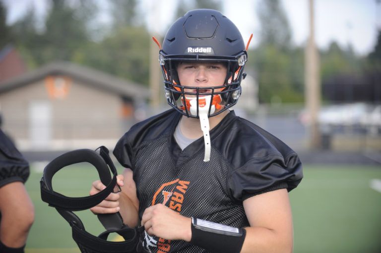 Washougal High School football players toss heavy blocking pads during drills at Fishback Stadium last month.