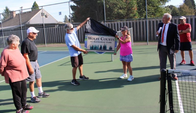 Washougal residents Tawn and Mike Wolfe (left) look on as a sign is revealed that proclaims that the pickleball courts at Hathaway Park have been named &quot;Wolfe Courts&quot; on Sept.