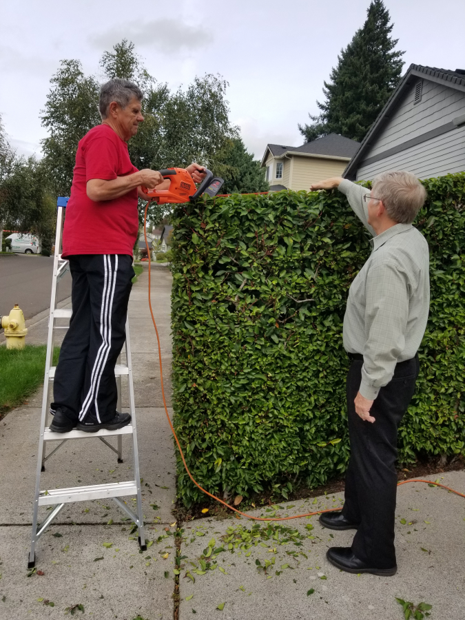 John Treosti (left), a volunteer with Villages Clark County, helps Villages chair John Chapman (right) with yard work.