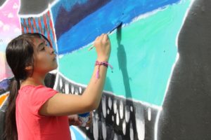 Jemtegaard Middle School Club 8 art student Abby Picho paints a section of a mural in Washougal on Saturday, Oct. 12. (Doug Flanagan/Post-Record)