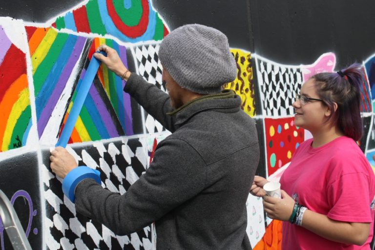 Washougal artist Travis London (left) assists Jemtegaard Middle School Club 8 art student Kylee Phillips with her section of a mural in Washougal on Saturday, Oct. 12.