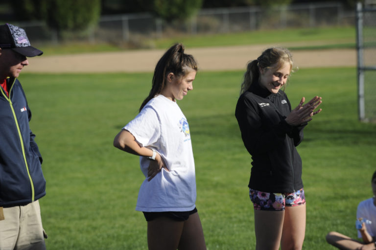 Camas High School runner Halle Jenkins (center) goes over the Papermakers&#039; racing accomplishments with sophomore Catelyn Flolo (right) during a recent practice session.