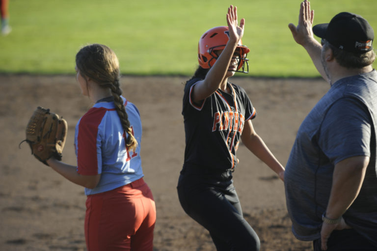 Washougal High School freshman Chloe Johnson high-fives a coach after using her speed to reach first base during the Panthers&#039; 9-5 win over Mark Morris High School on Oct. 23.