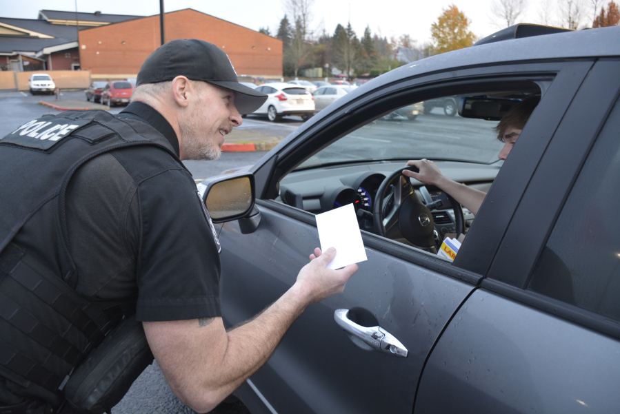 Washougal police officer Kelly Anderson rewards a Washogual High student with a Dutch Bros. gift certificate for wearing a seat belt Nov. 13. (contributed photo courtesy of Washougal School District)
