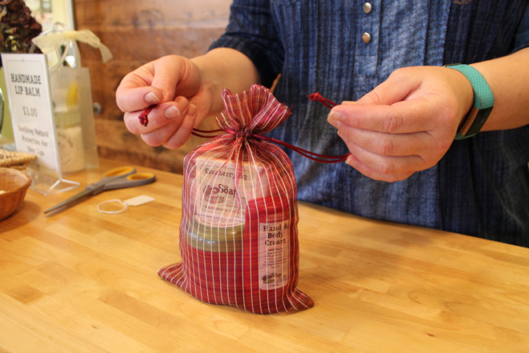 Soap Chest employee Michelle Hughes ties the bow on a gift bag filled with cranberry-scented body products on Nov. 22.