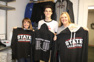 Sheryl Obegi, Tommy Kelly and Karen Gibson show off some of the Camas football shirts available at Obegi and Gibson's new business, Papermaker Pride. Kelly, a senior at Camas High School, is working at the new downtown Camas business as part of his senior project on marketing research. (Photos by Kelly Moyer/Post-Record)