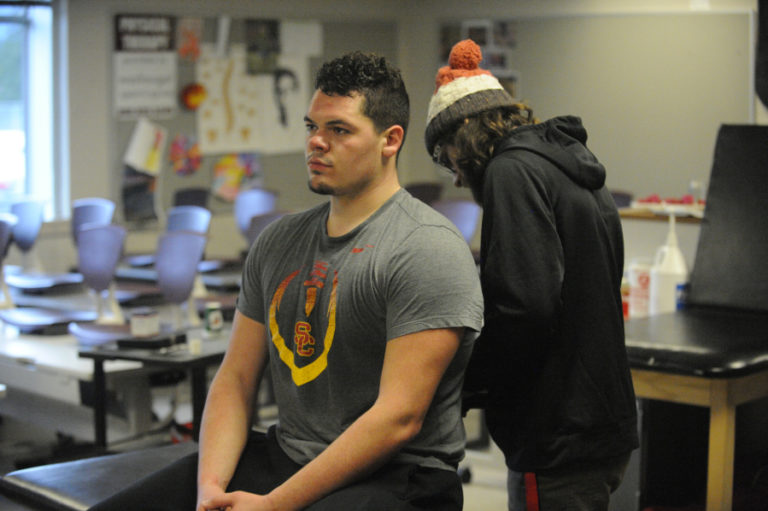 Camas High School left tackle Caadyn Stephen recieves lower back therapy from Camas athletic trainer Jake Howell.