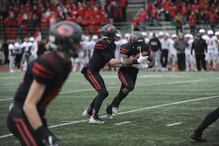 Camas High School quarterback Blake Asciutto (center) hands off to Jacques Badolato-Birdsell, with wide receiver Jackson Clemmer in the foreground, on Nov.