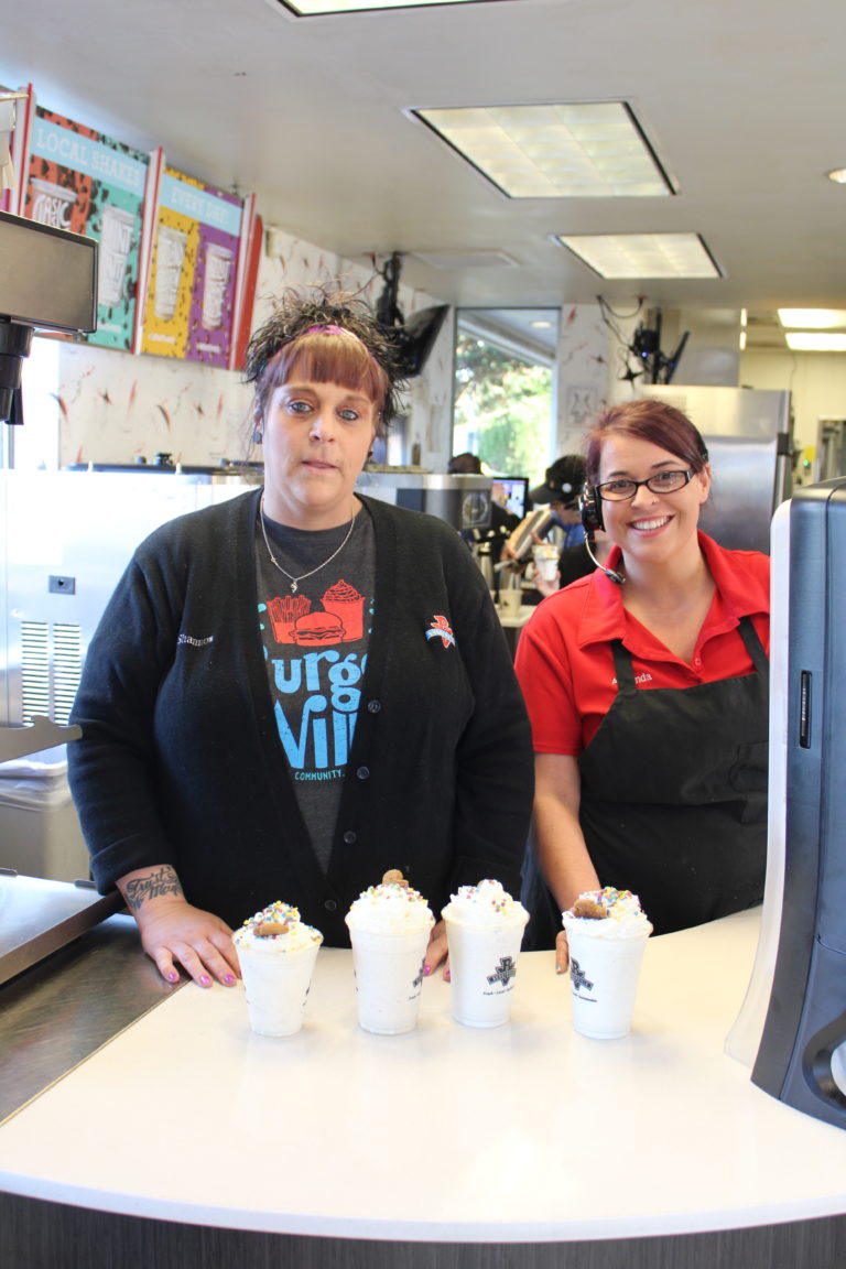 Shannon Lindberg (left), a team manager at the Vancouver Heights Burgerville, and Amanda McIntyre (right), a team manager at the Camas Burgerville, serve four of the restaurant’s seasonal gingerbread shakes, which use ingredients from a Camas couple’s cookie company, on Thursday, Dec.