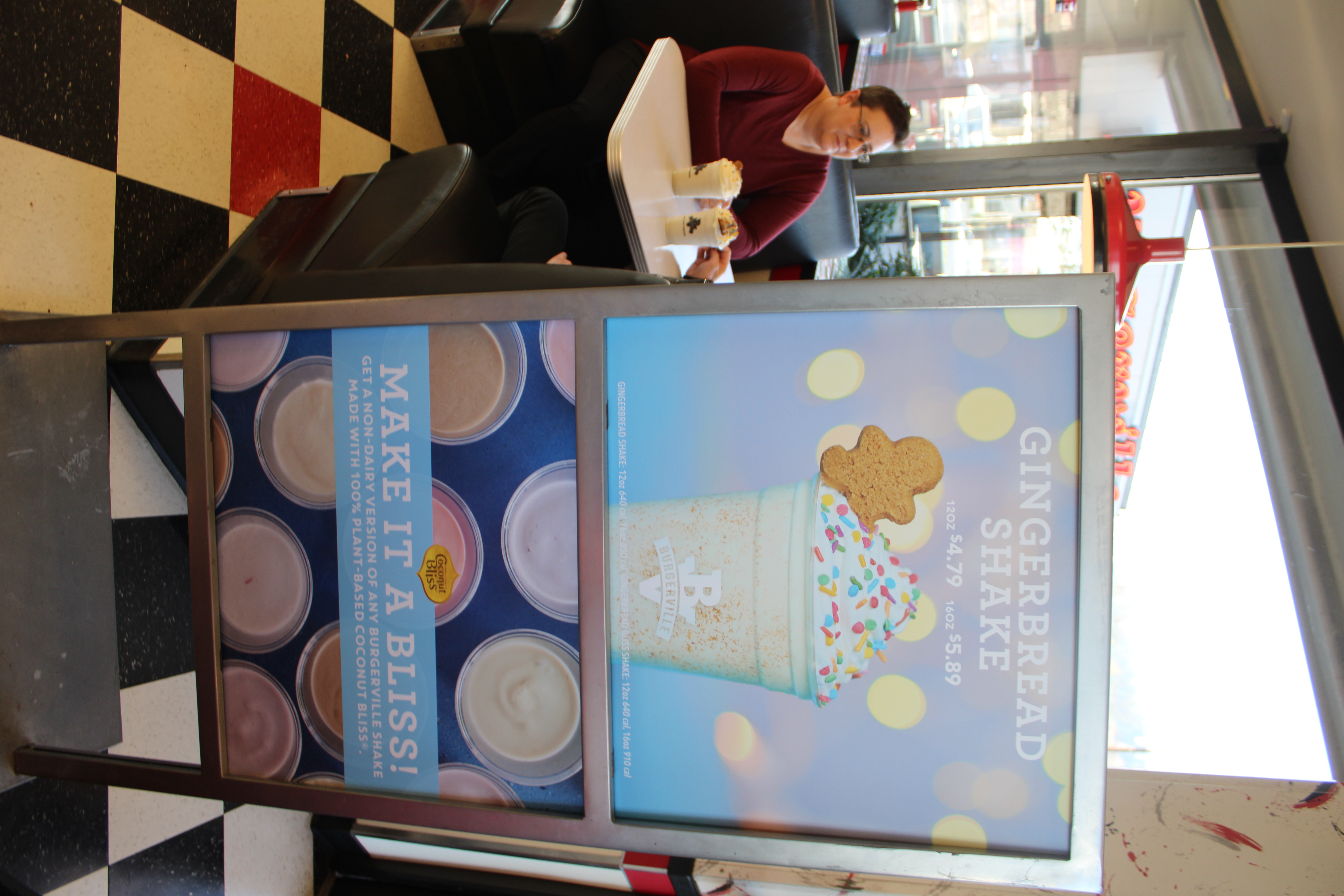 A sign advertising Burgerville’s seasonal Gingerbread Shake sits near the entrance of the Camas Burgerville, while Karen Wood, of Camas, co-owner of McTavish Shortbread, the company that supplied the gingerbread cookies for the seasonal shake, talks to her husband and business partner, Peter Wood (not pictured) on Thursday, Dec. 5.