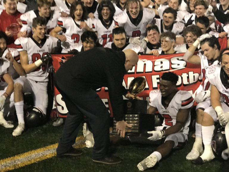 The 4A state championship trophy is held by junior Jacques Badolato-Birdsell as the Camas High School football team poses for photographs after beating Bothell High School on Dec. 7.