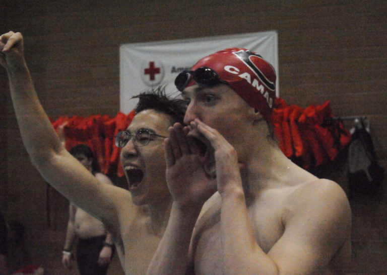 Camas boys swimming and diving captains Jaiden Kim (left) and Luke Bales (right) fire up their teammates at the District 4 championship meet in Kelso on Feb. 7.