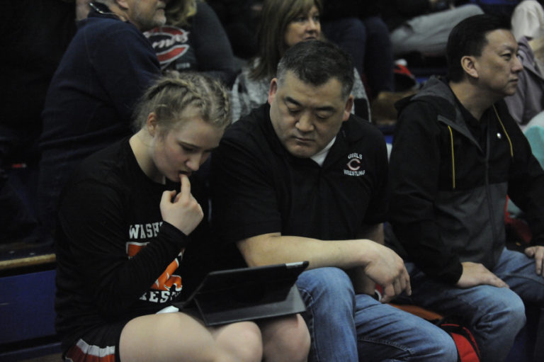 Washougal&#039;s Ashley Garrison (left) gets advice from her Camas girls wrestling coach Mark Yamashita (right), her club coach, at the Region 3 meet in Kelso on Feb. 15.