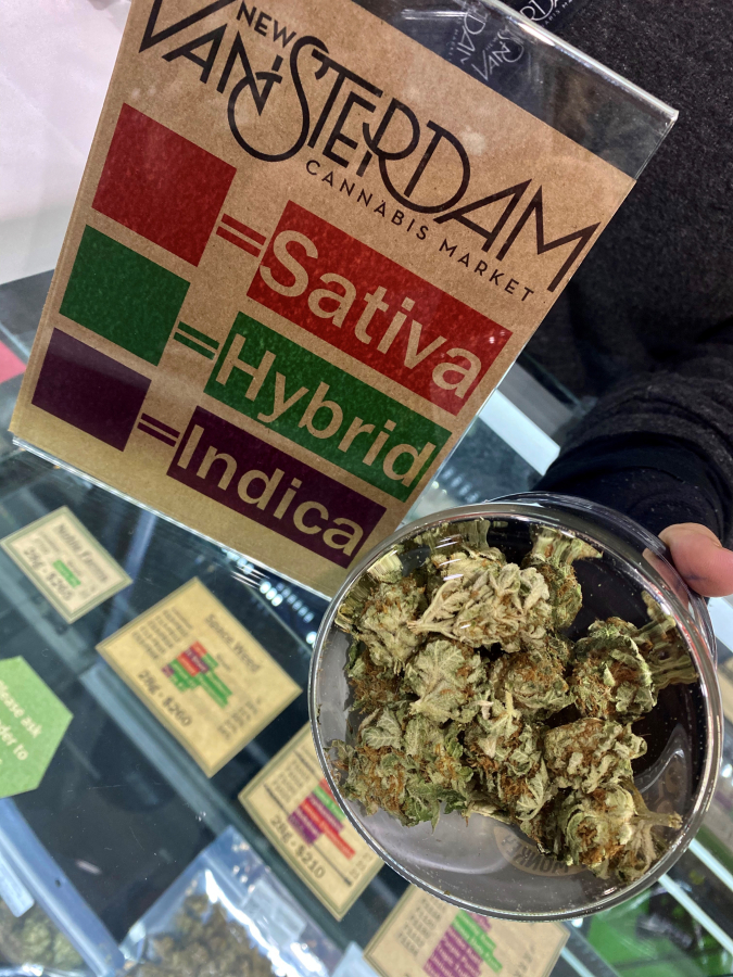 The manager of the New Vansterdam cannabis shop in Vancouver shows an example of cannabis flowers available for purchase.