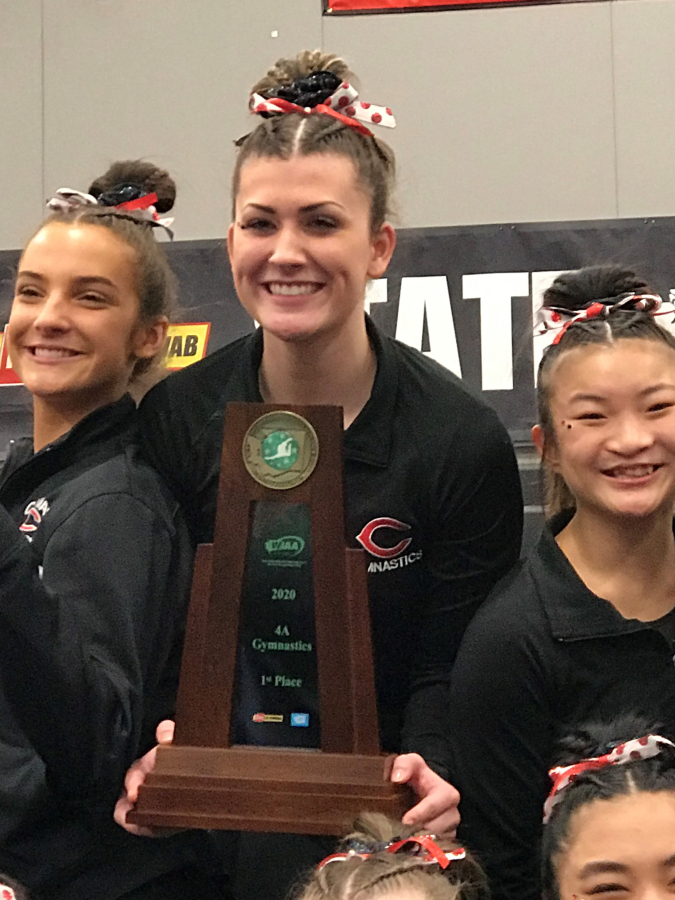 From left to right, Camas gymnasts Siena Brophy, Lizzy Wing and Julia Marsh cradle the 4A state championship trophy on Feb. 21 in Bellevue.