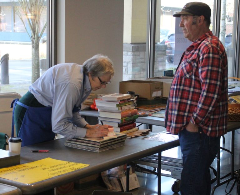 Sallie Tucker of Friends of Washougal Community Library (left) assists a customer during a book sale in downtown Washougal on Friday, Feb.  28.