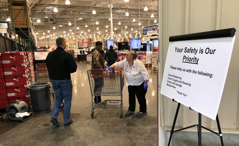 An employee wipes down a shopping cart at the Camas Costco store on Friday, March 13.