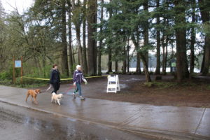 (Kelly Moyer/Post-Record) Valerie McOmie (right) and Julian McOmie (left), of Camas, walk their dogs, Katie (with Julian) and Max (with Valerie), past a closed-off parking lot near Round Lake in Camas on Tuesday, March 31. The city of Camas on Tuesday closed parking lots at the city's parks and trailheads to help reduce the spread of COVID-19. 