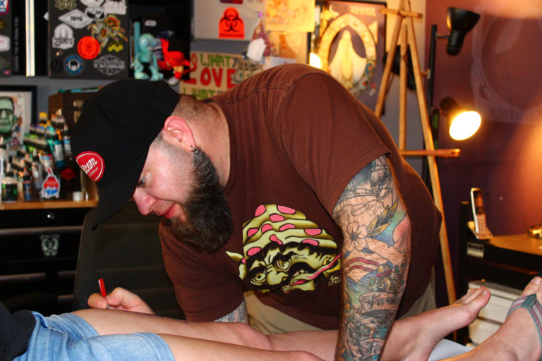 (Post-Record file photo) Ryan Boomhower, owner of 3rd Heart Tattoo in downtown Washougal, prepares his client, Tiffany Renteria, of Vancouver, for her new tattoo, in April 2018.