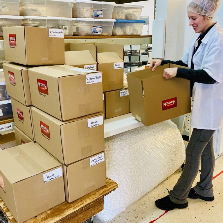 A McTavish Shortbread worker stacks "Cookies for Caregivers" boxes filled with shortbread cookies meant for caregivers working on the front lines of the COVID-19 pandemic.