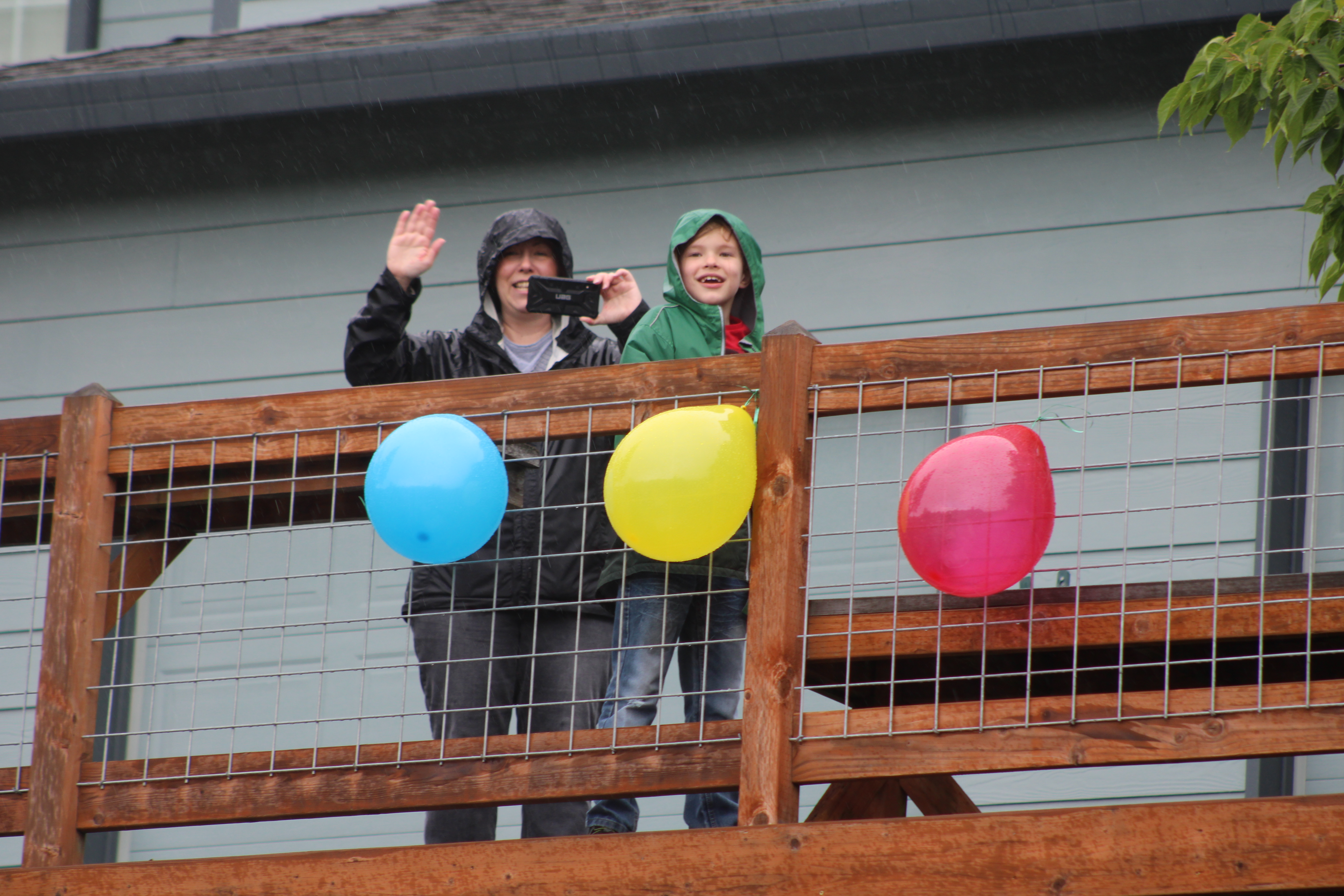 Timothy Hergenroether and his mother, Jessica, stand on a balcony outside their Camas home on Sunday, May 3, and wave to drivers passing by the home in a parade celebrating Timothy's eighth birthday. 