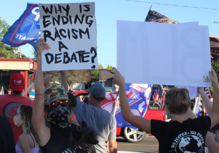 A Black Lives Matter supporter holds a sign asking, &quot;Why is ending racism a debate?&quot; in downtown Camas on Aug.