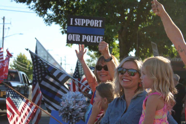 Women and children waves flags and hold "support our police" signs at a pro-police "Back the Blue" rally along Northeast Third Avenue in downtown Camas on Friday, Aug.