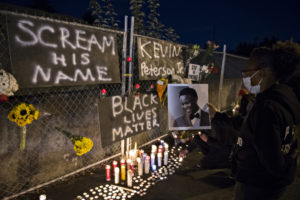 Alisha, one of the event organizers who declined to give her last name, holds a photo of Kevin Peterson Jr., a 21-year-old Black Camas man who was killed Thursday, Oct. 29, as he is remembered with a candlelight vigil at the Hazel Dell branch of U.S. Bank on Oct. 30 . (Photo courtesy of Amanda Cowan/The Columbian)