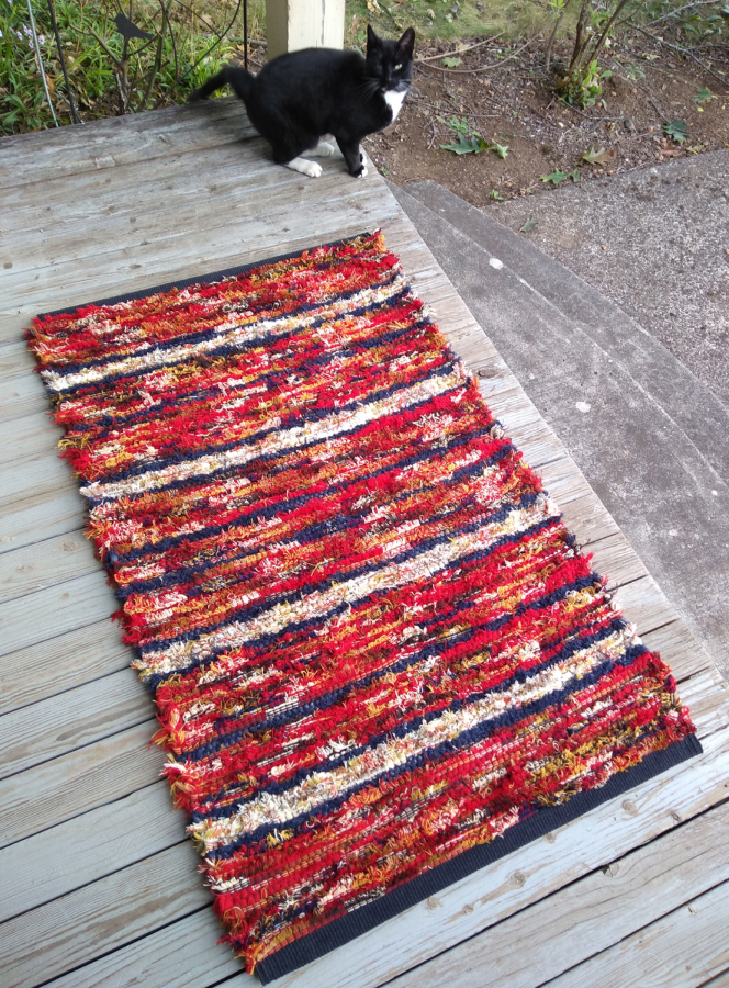 Contributed photo courtesy of Kathy Marty 
 A cat stands next to a rug crafted by Washougal weaver Kathy Marty.