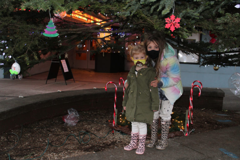 Sisters Ava, 3, (left) and Elle, 6, (right) play under the lighted holiday tree in downtown Camas on Dec.
