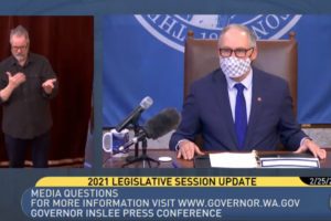 Washington Gov. Jay Inslee (right), accompanied by a sign language interpreter (left), speaks about COVID-19 rates during a remote press conference on Thursday, Feb. 25, 2021. (Screenshot by Kelly Moyer/Post-Record)