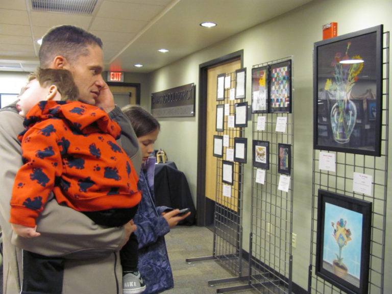 Jeff Snell, then the assistant superintendent of the Camas School District, holds his son, Micah, and listens to students describe their work at a Camas High School art show in 2012, with his daughter, Mackenzie.
