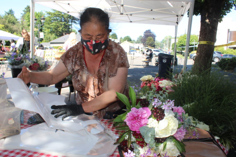 Flower vendor Xia Chang prepares a bouquet of flowers grown in Camas at the Camas Farmers Market on Wednesday, June 2, 2021. (Kelly Moyer/Post-Record)