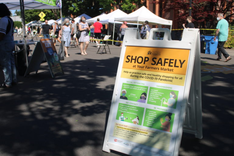 COVID-19 safety precautions, including the wearing of face coverings and social distancing, are in effect at the 2021 Camas Farmers Market. A sign details the safety rules at the first market of the 2021 season on Wednesday, June 2, 2021. (Kelly Moyer/Post-Record)