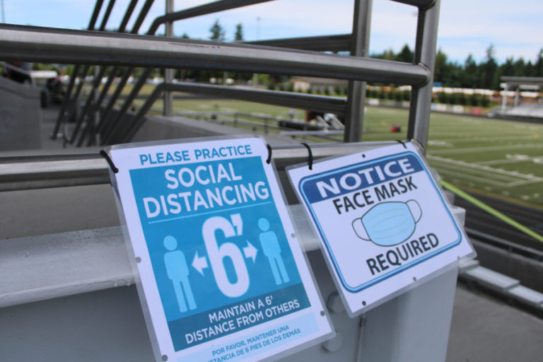 COVID-19 safety signs ask people to distance and wear face masks at the 2021 Hayes Freedom High School graduation ceremony, held Saturday, June 12, 2021, at Doc Harris Stadium in Camas.