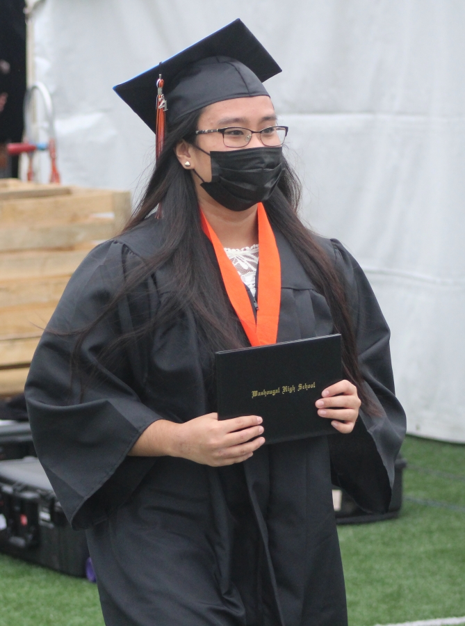 Left: A Washougal High School senior from the class of 2021 earns their diploma during the school&#039;s high school graduation ceremony on Saturday, June 12, 2021, at Fishback Stadium in Washougal.