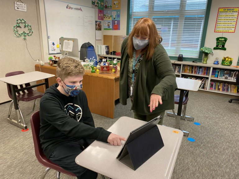 Canyon Creek Middle School teacher Katherine Baxter (right) helps student Noah Dentler work on a problem during a class session in 2021.