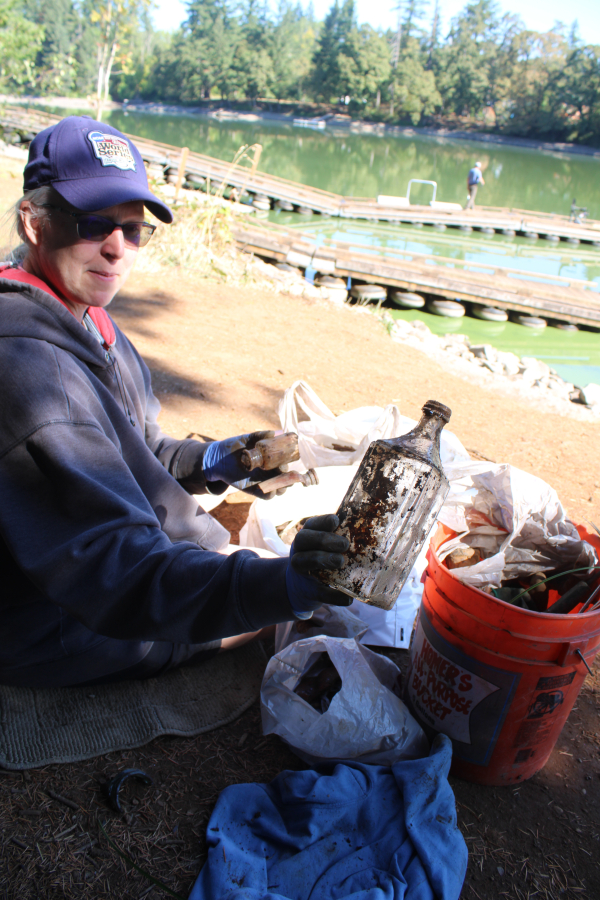 Lisa Tangen, of Vancouver, holds a bottle she and her husband, Tom Tange (not pictured), discovered during the annual Lacamas Lake Cleanup on Saturday, Sept.