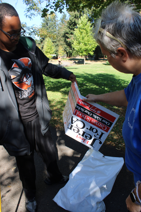 Jordan Densmore, 15, (left) and his grandmother, Sherry Warren (right), both of Portland, show an election sign they pulled from the shores of Lacamas Lake during the annual lake cleanup on Saturday, Sept.