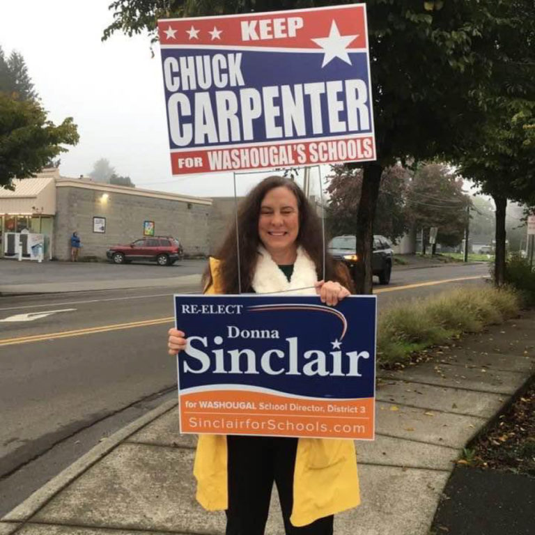 Washougal School Board member Donna Sinclair holds signs in support of herself and her fellow board member, Chuck Carpenter, during a sign-waving event before the Nov. 2, 2021 election.